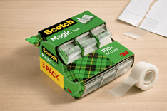 Scotch Magic Tape roll in desktop dispenser applied on paper for invisible repair and clean finish